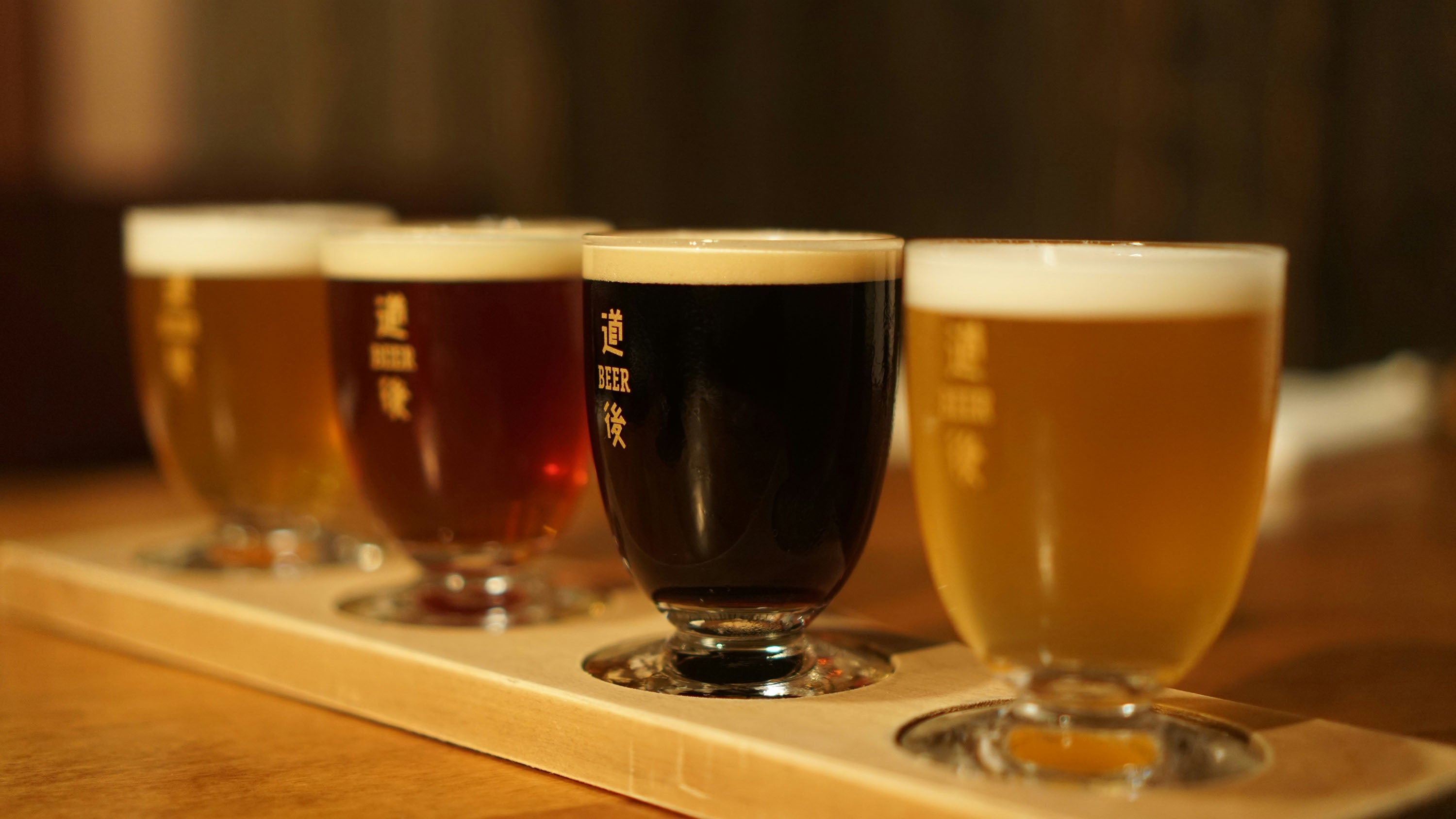 Four glasses of craft beer in a tasting tray.