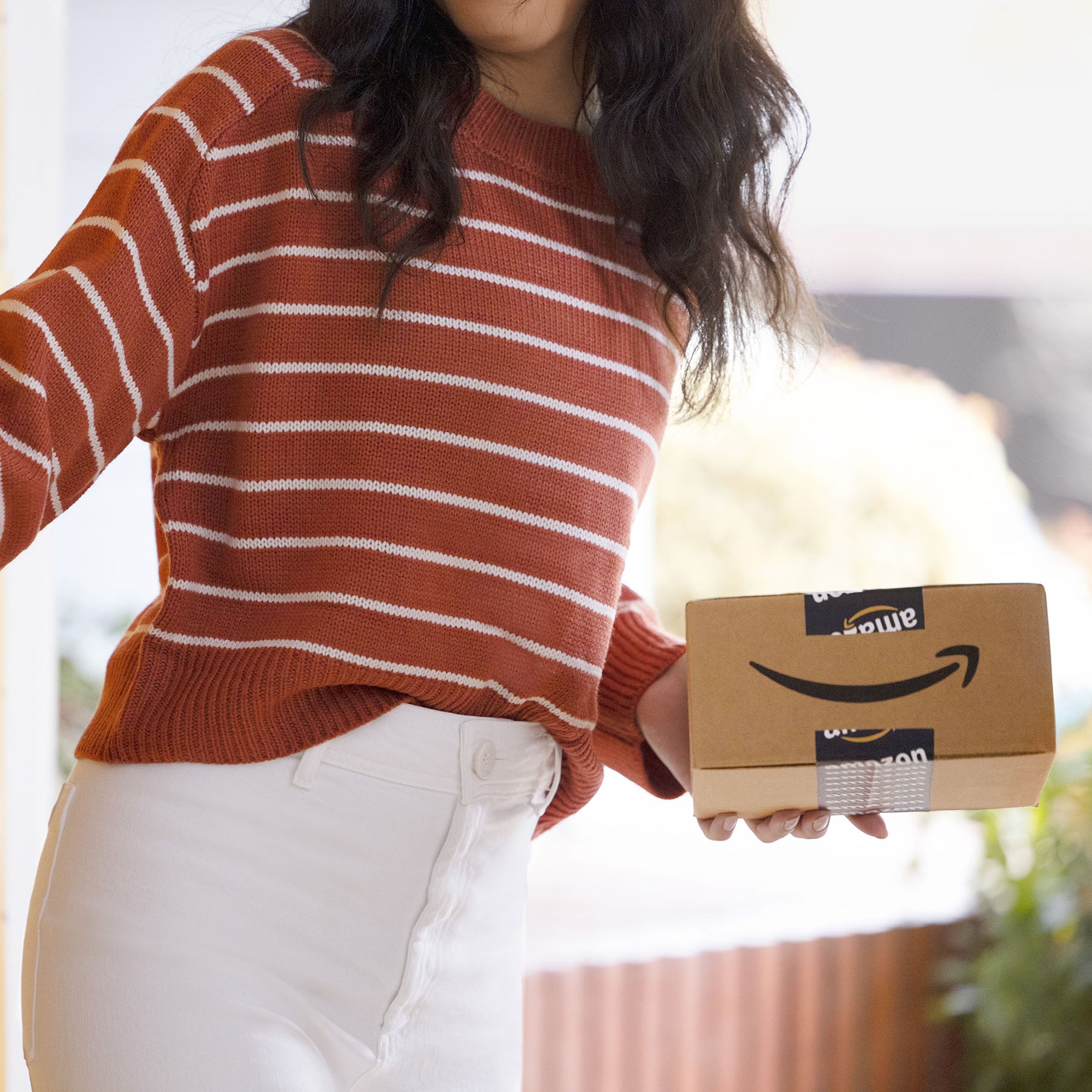 A person on a striped sweater with Amazon delivery box.
